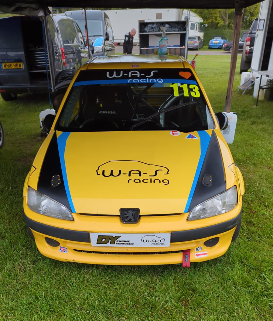 ES racing car parked up with the pit board leaning against the bonnet showing the fastest time of the day